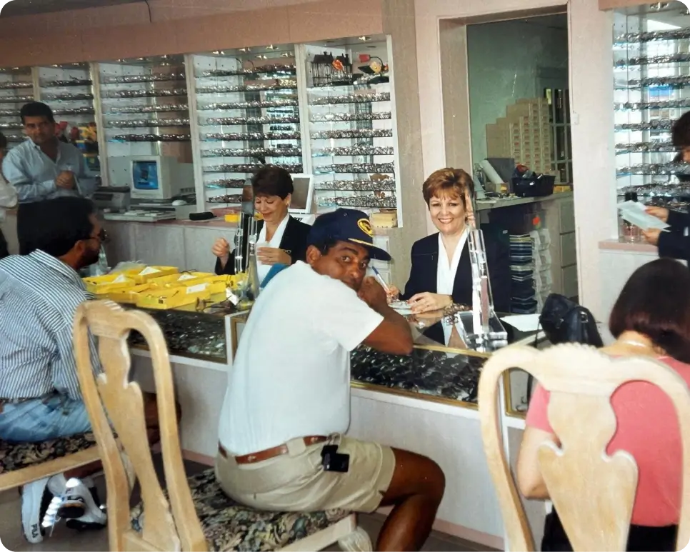 a man sitting at a counter with a woman in front of him Elios optical